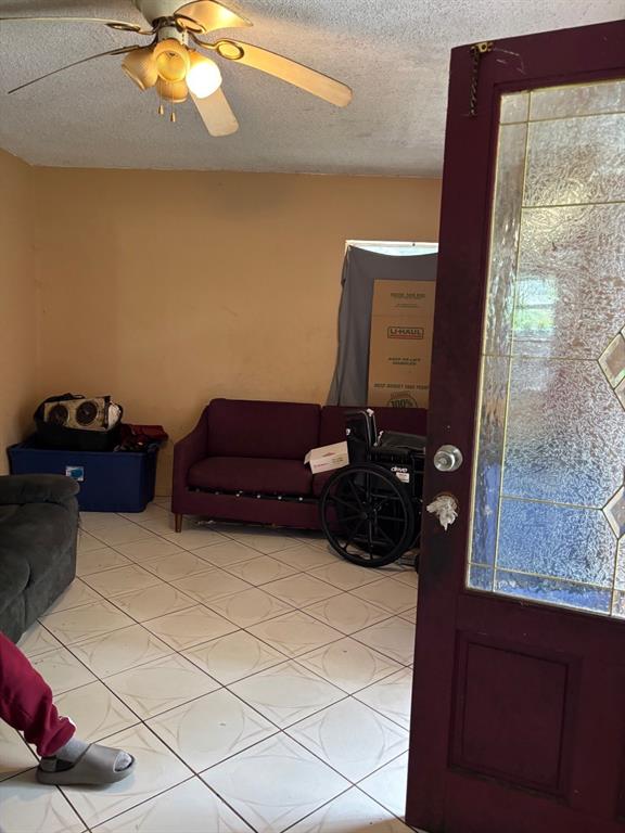 A living room with tiled floors, a ceiling fan, a purple sofa, and a wheelchair — 1014 37TH STREET, ORLANDO, FL