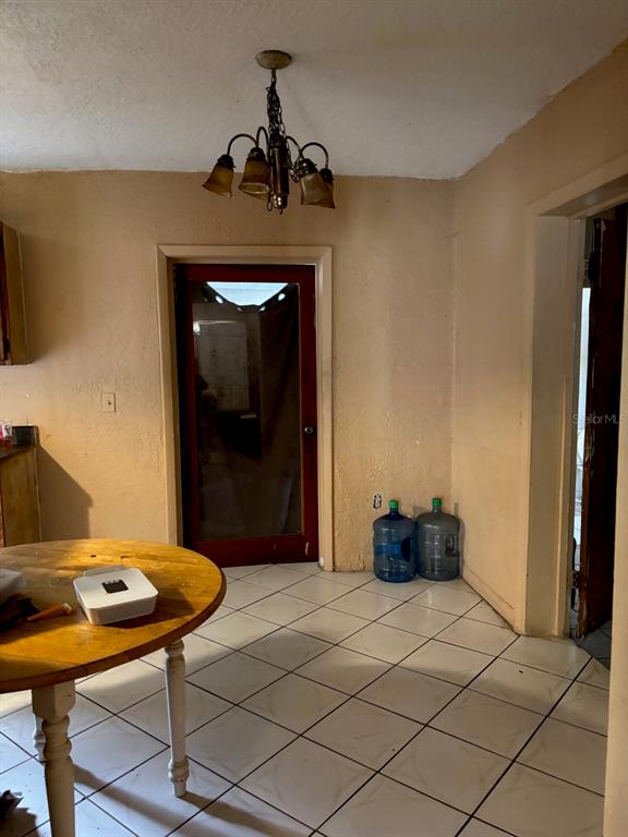 A dining area features a round wooden table, a chandelier, and tiled flooring — 1014 37TH STREET, ORLANDO, FL