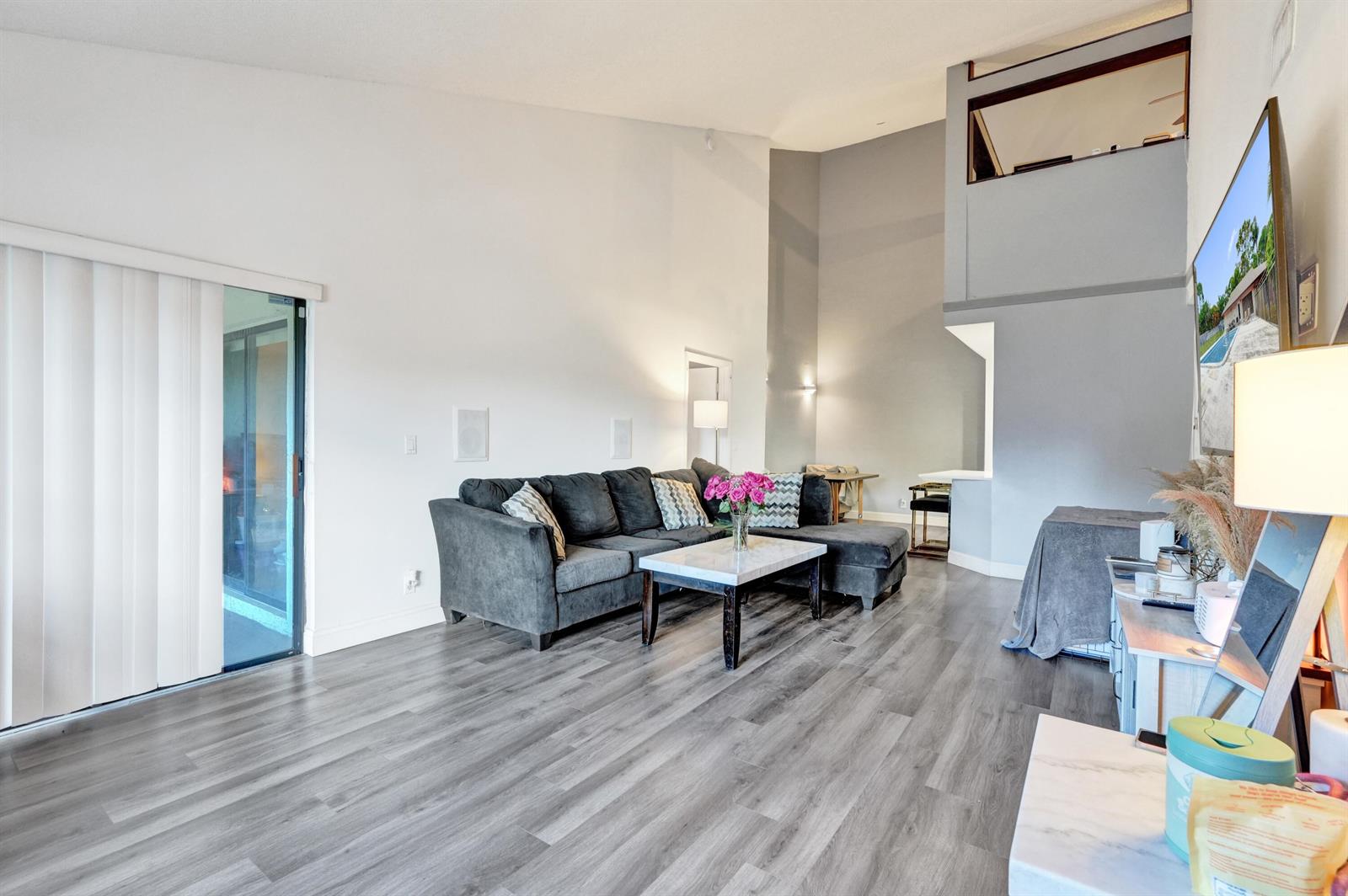 A living room features vaulted ceilings, gray wood-look flooring, a sectional sofa, and a loft — 4225 S 57th Avenue, FL 33463, FL