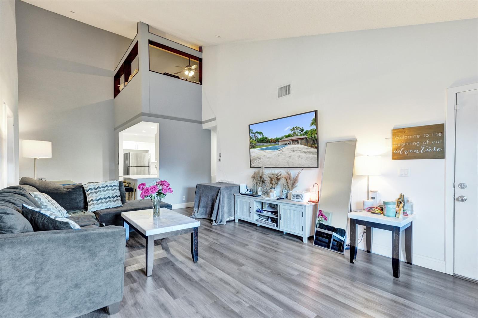 A living room features gray wood-look flooring, a sectional sofa, and a wall-mounted television — 4225 S 57th Avenue, FL 33463, FL