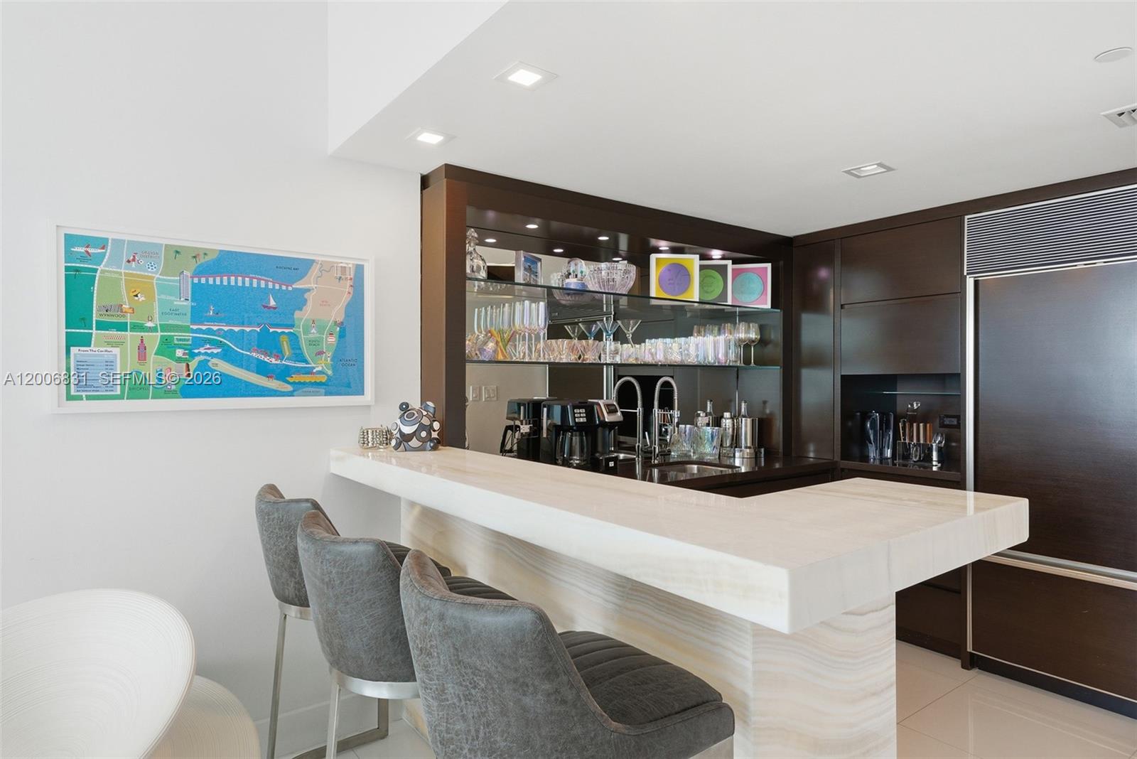 A modern home bar features a stone countertop, dark wood cabinetry, and three gray stools — 6801 Collins Ave, Miami Beach FL 33141, MIAMI BEACH, FL