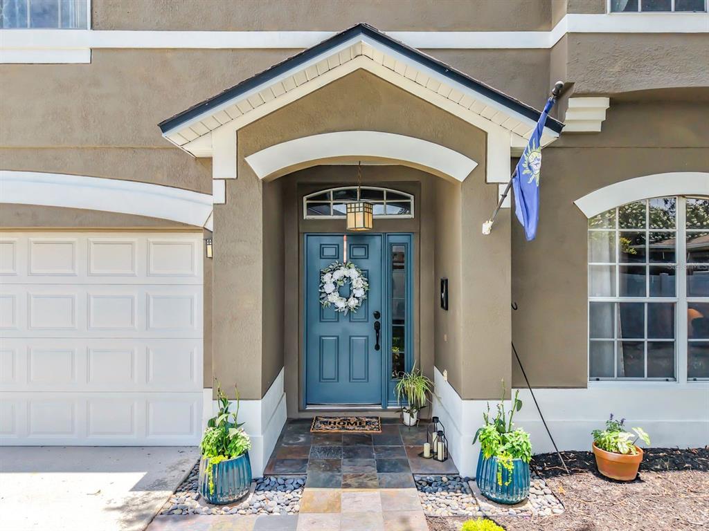 The exterior of a house features a blue front door, a wreath, and a garage — 14664 SAINT GEORGES HILL DRIVE, ORLANDO, FL