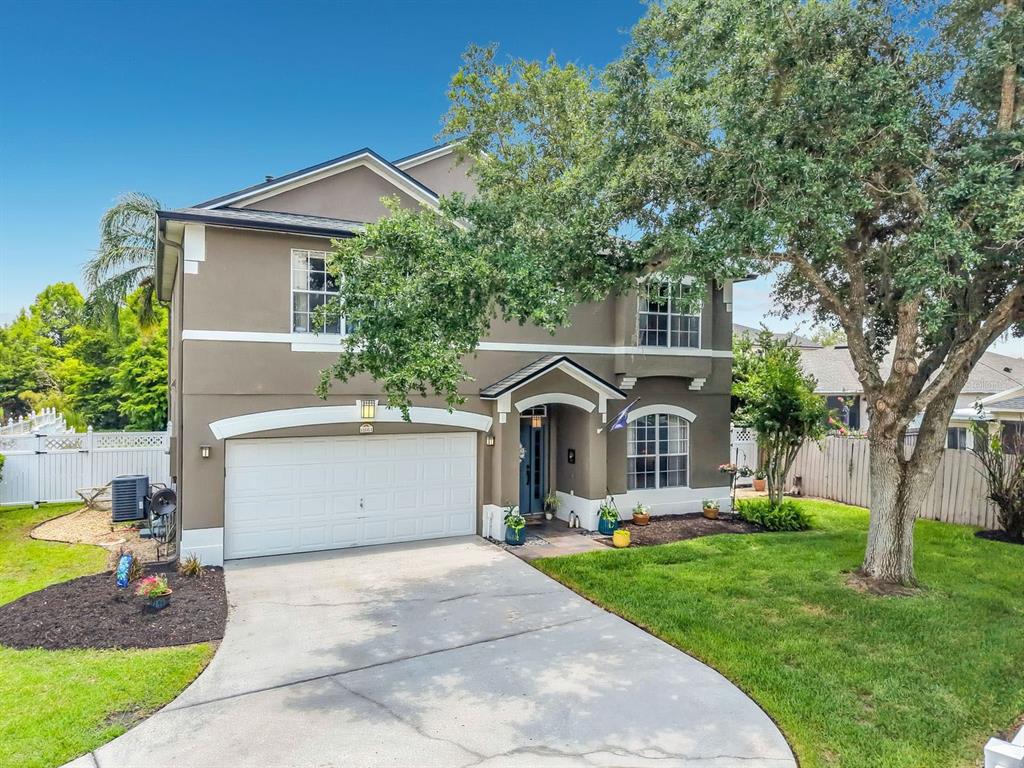 A two-story suburban house with a tan stucco exterior, white trim, and a two-car garage — 14664 SAINT GEORGES HILL DRIVE, ORLANDO, FL