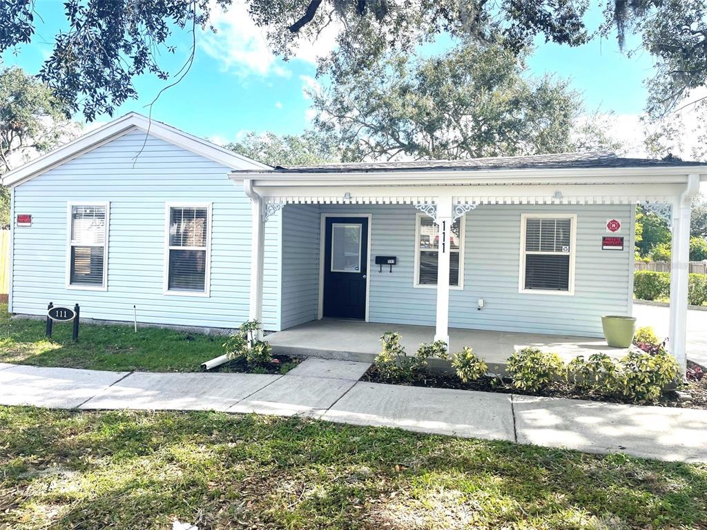 A light blue, single-story house features a covered front porch and a black front door — 111 S RANDOLPH AVENUE, KISSIMMEE, FL