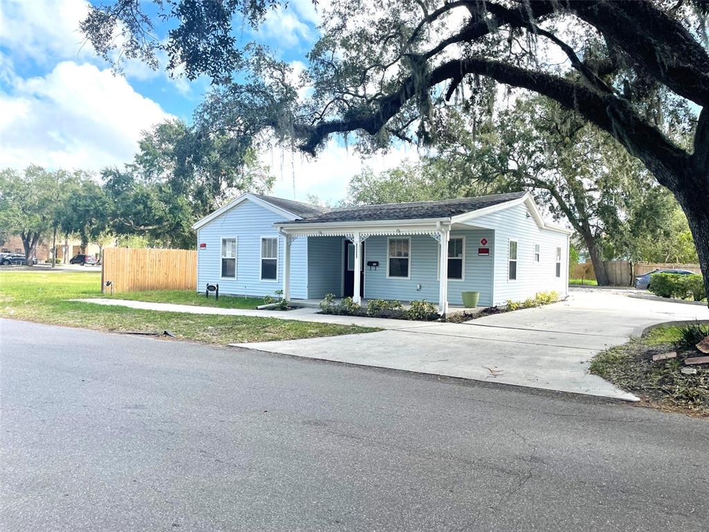 A light blue single-story house features a front porch, a concrete driveway, and large trees — 111 S RANDOLPH AVENUE, KISSIMMEE, FL