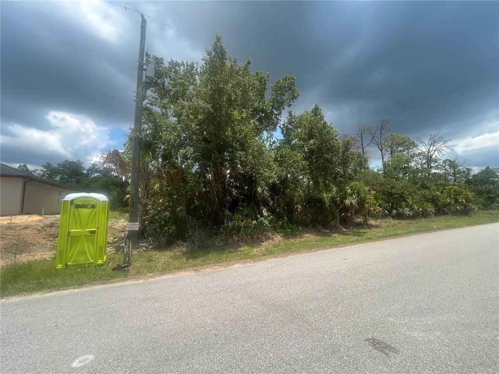 A vacant, wooded lot sits next to a portable toilet and a utility pole — 1623 LACE TERRACE, PORT CHARLOTTE, FL