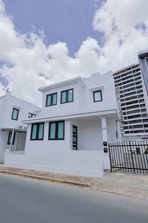 A two-story white building with dark-framed windows stands next to a tall apartment tower — 1717 CALLE COLON, SANTURCE, PR