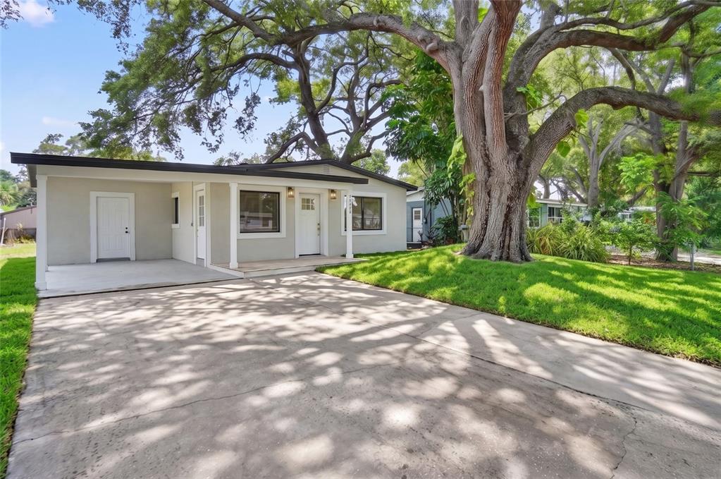 A single-story house with a concrete driveway, a large tree, and a covered front porch — 5641 92ND TERRACE N, PINELLAS PARK, FL