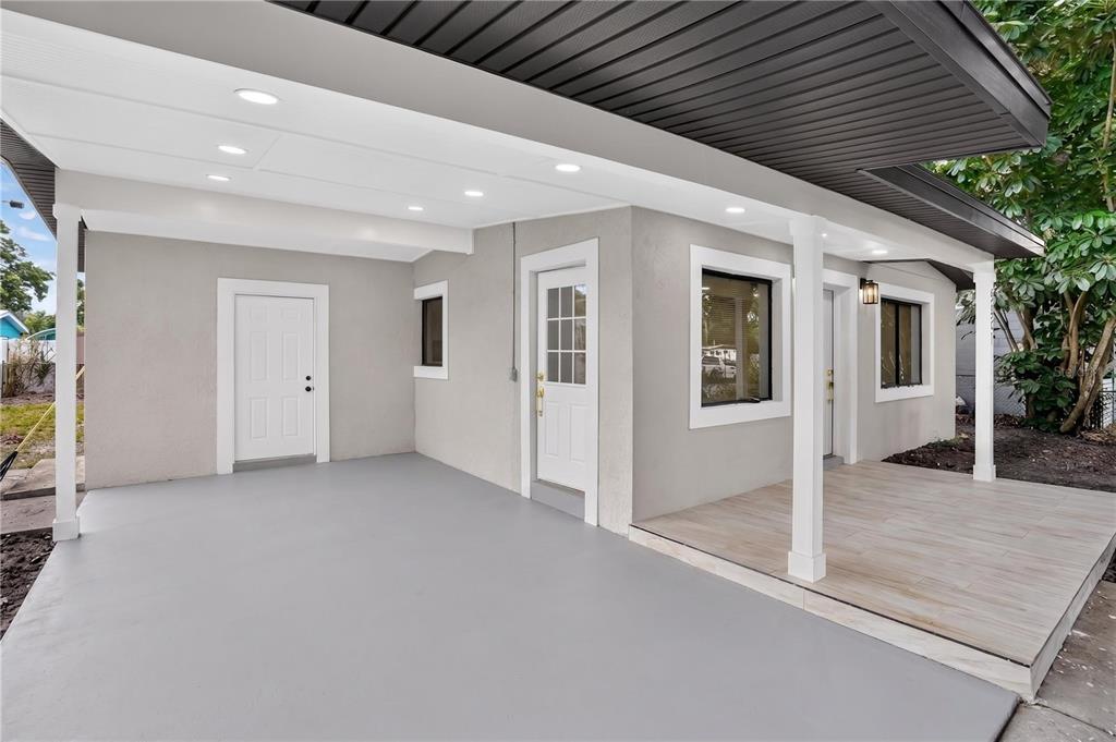 A gray-painted carport with a white door and an adjacent tiled porch area — 5641 92ND TERRACE N, PINELLAS PARK, FL