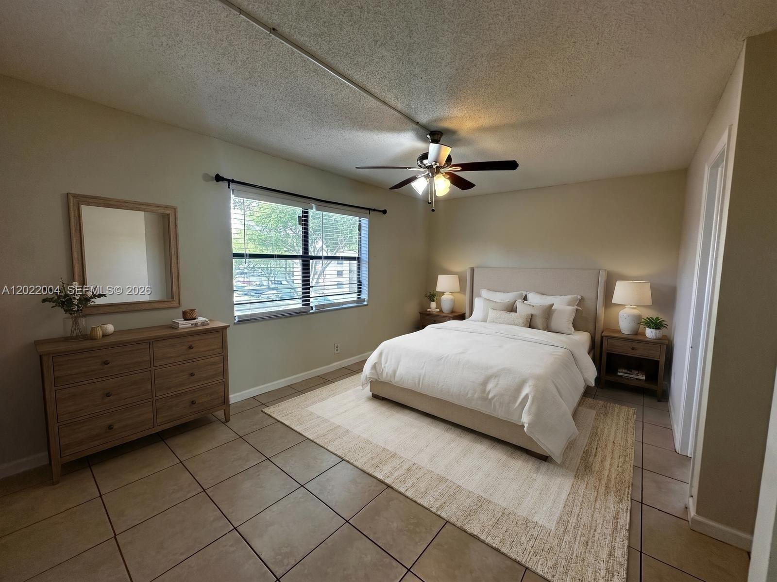 A bedroom features a bed, dresser, ceiling fan, and tile flooring under a window — 3400 Foxcroft Rd # 301, Miramar FL 33025, MIRAMAR, FL