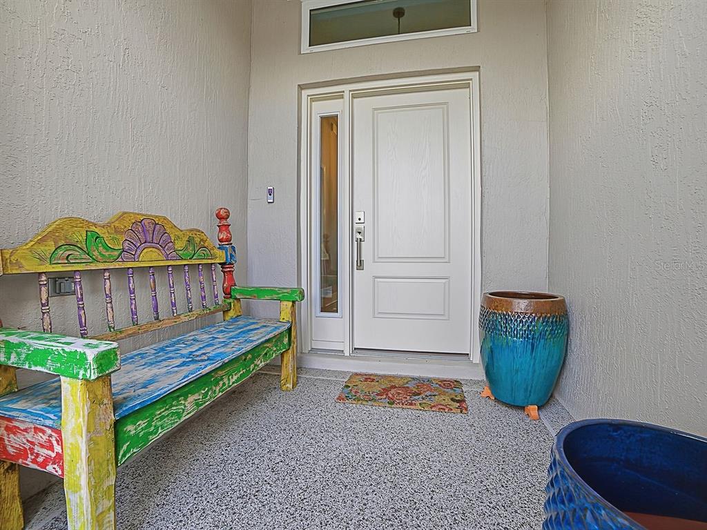 A front entryway features a colorful wooden bench, two large planters, and a white door — 4258 WIDMANN PLACE, THE VILLAGES, FL
