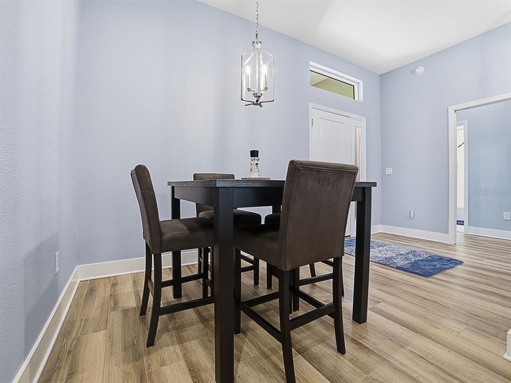 A dining area features a dark wood table with four chairs under a pendant light — 4258 WIDMANN PLACE, THE VILLAGES, FL
