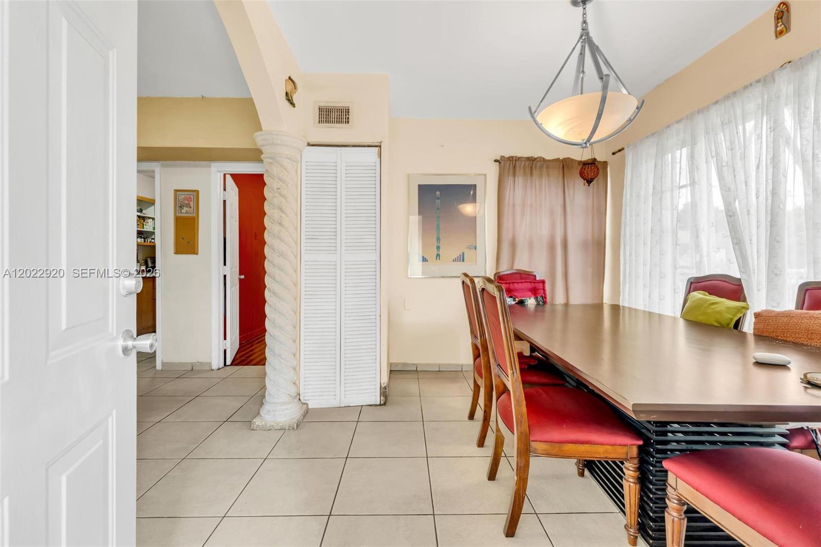 A dining room features a wooden table, red chairs, tile flooring, and a decorative column — 1122 NW 38th St, Miami FL 33127, MIAMI, FL