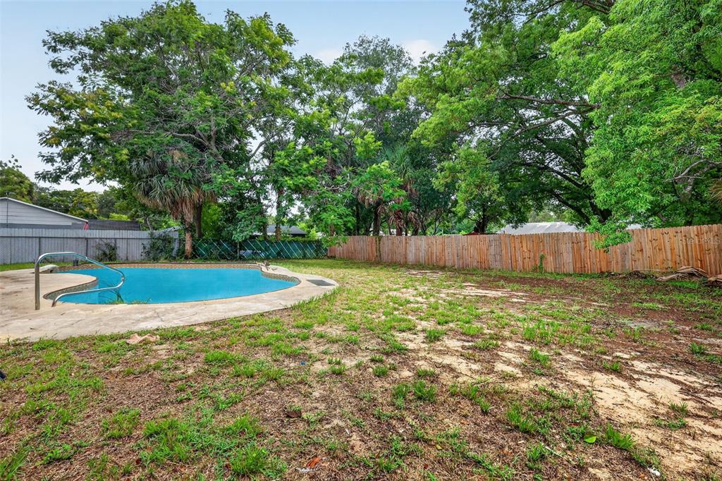 A backyard featuring a swimming pool, patchy grass, and a wooden privacy fence — 1877 WAYSIDE DRIVE, ORLANDO, FL