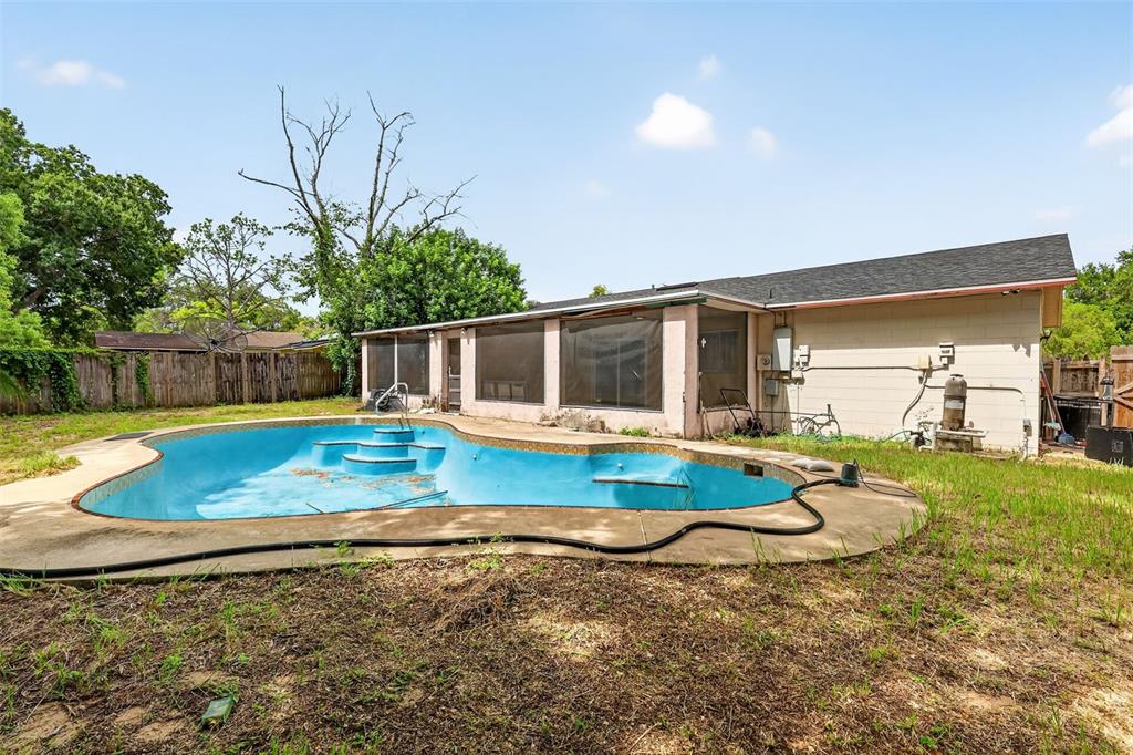 An outdoor view of a backyard with an empty swimming pool and a screened-in patio — 1877 WAYSIDE DRIVE, ORLANDO, FL