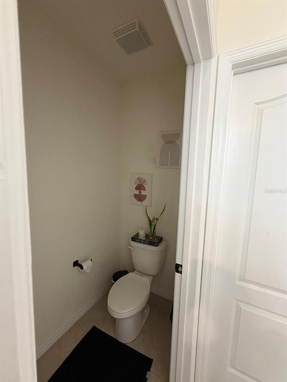 A small bathroom features a white toilet, neutral walls, and two framed wall art pieces — 5268 MADDIE DRIVE, HAINES CITY, FL