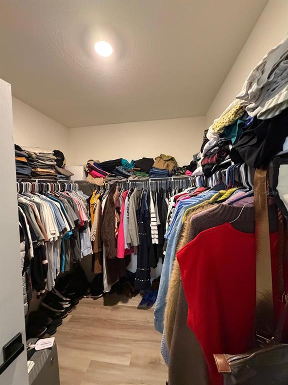 A walk-in closet features wire shelving, hanging clothes, and light-colored wood-look flooring — 5268 MADDIE DRIVE, HAINES CITY, FL