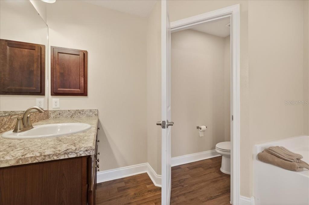 A bathroom features a vanity with a stone countertop, dark wood cabinets, and a toilet — 15 KANE PLACE, PALM COAST, FL