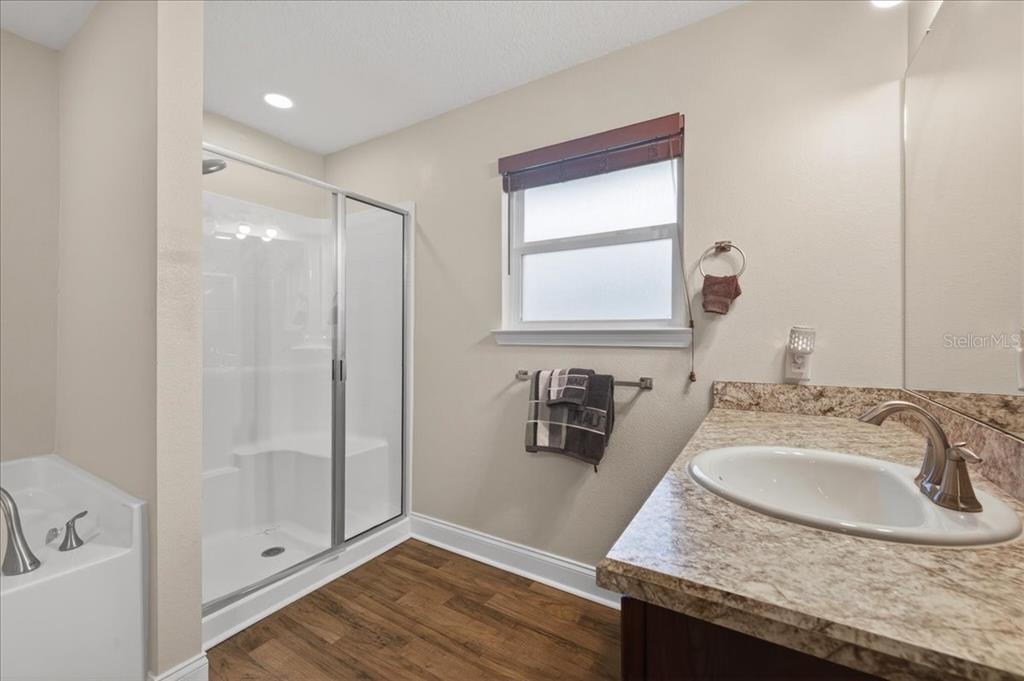 A bathroom features a walk-in shower, a soaking tub, and a granite-topped vanity — 15 KANE PLACE, PALM COAST, FL