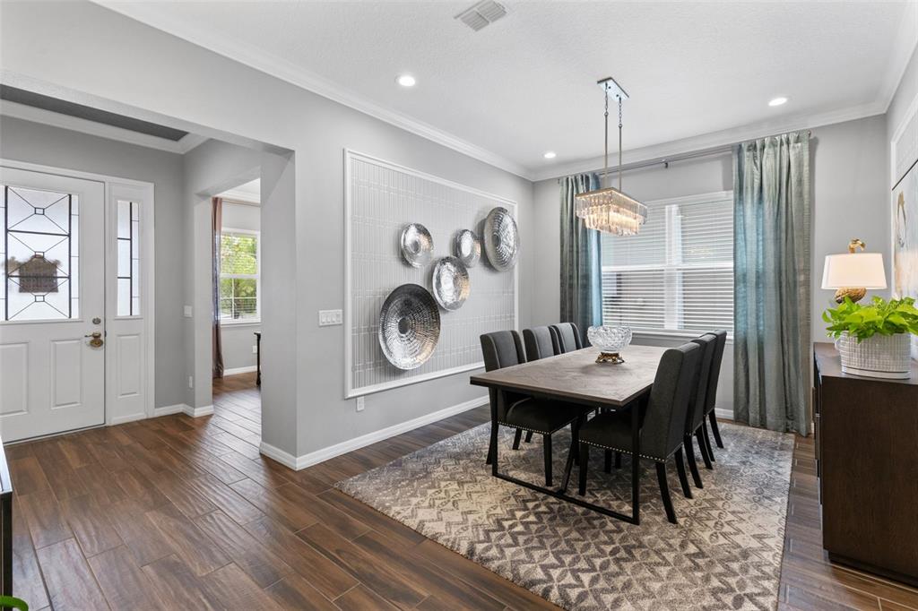 A dining room features a dark wood table, gray upholstered chairs, and metallic wall decor — 1448 LAKE FLORENCE WAY, WINTER PARK, FL