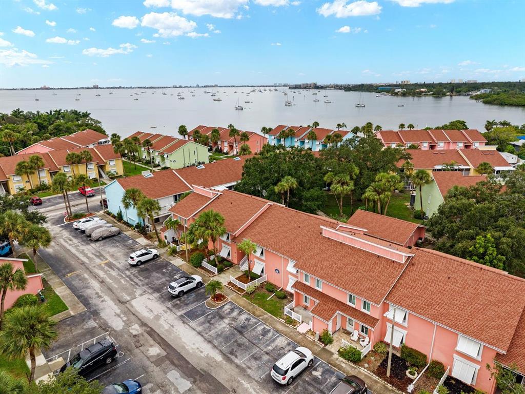 An aerial view shows multi-story pink and green townhomes near a large body of water — 3675 41ST WAY S UNIT I, ST PETERSBURG, FL