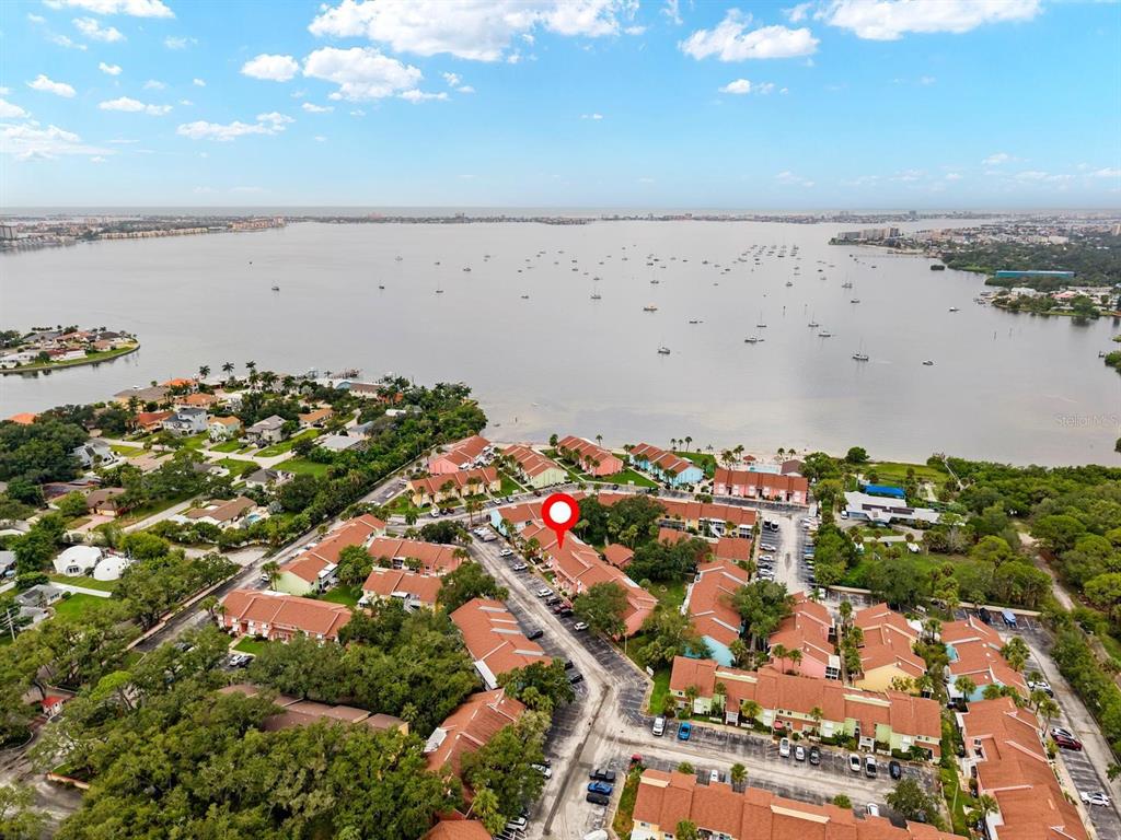 An aerial view shows a residential complex with red-roofed buildings near a large body of water — 3675 41ST WAY S UNIT I, ST PETERSBURG, FL