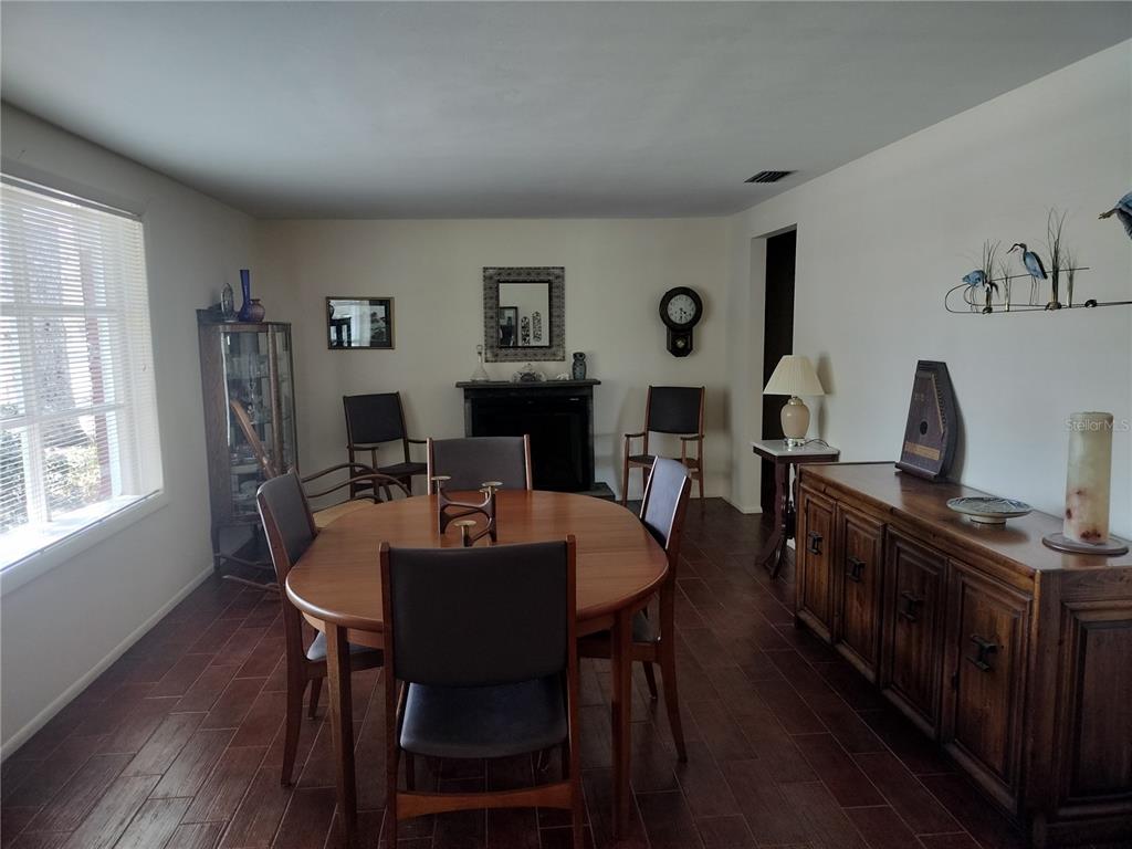 A dining room features a wooden table, chairs, a fireplace, and a large sideboard — 39133 5TH AVENUE, ZEPHYRHILLS, FL