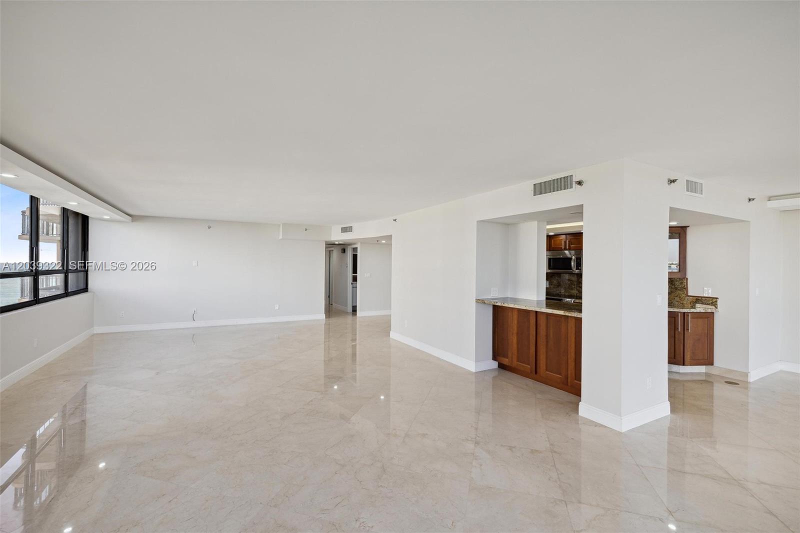 An open-concept living area features polished tile floors, white walls, and a wood-cabinet kitchen — 10175 Collins Ave # 907, Bal Harbour FL 33154, BAL HARBOUR, FL