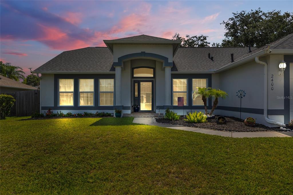 A single-story house with a gray exterior, a covered entryway, and a green lawn — 2400 WOLF CREEK DRIVE, MELBOURNE, FL