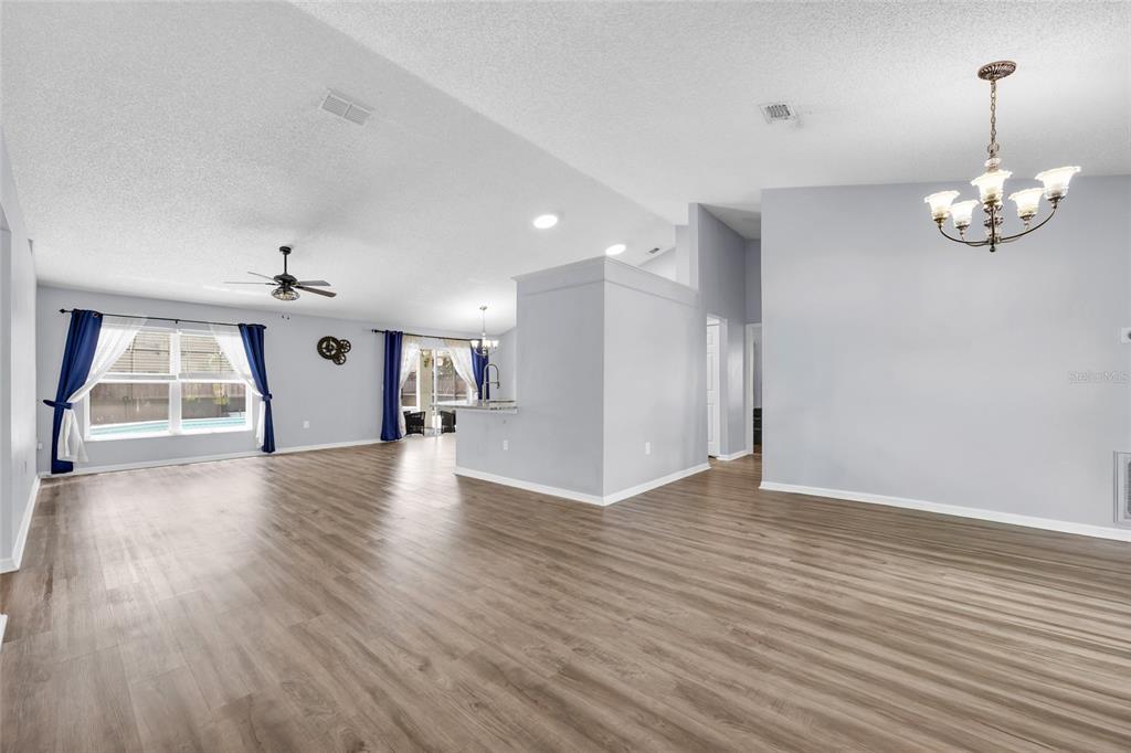 An open-concept living and dining area features light wood flooring, neutral walls, and modern furniture — 2400 WOLF CREEK DRIVE, MELBOURNE, FL