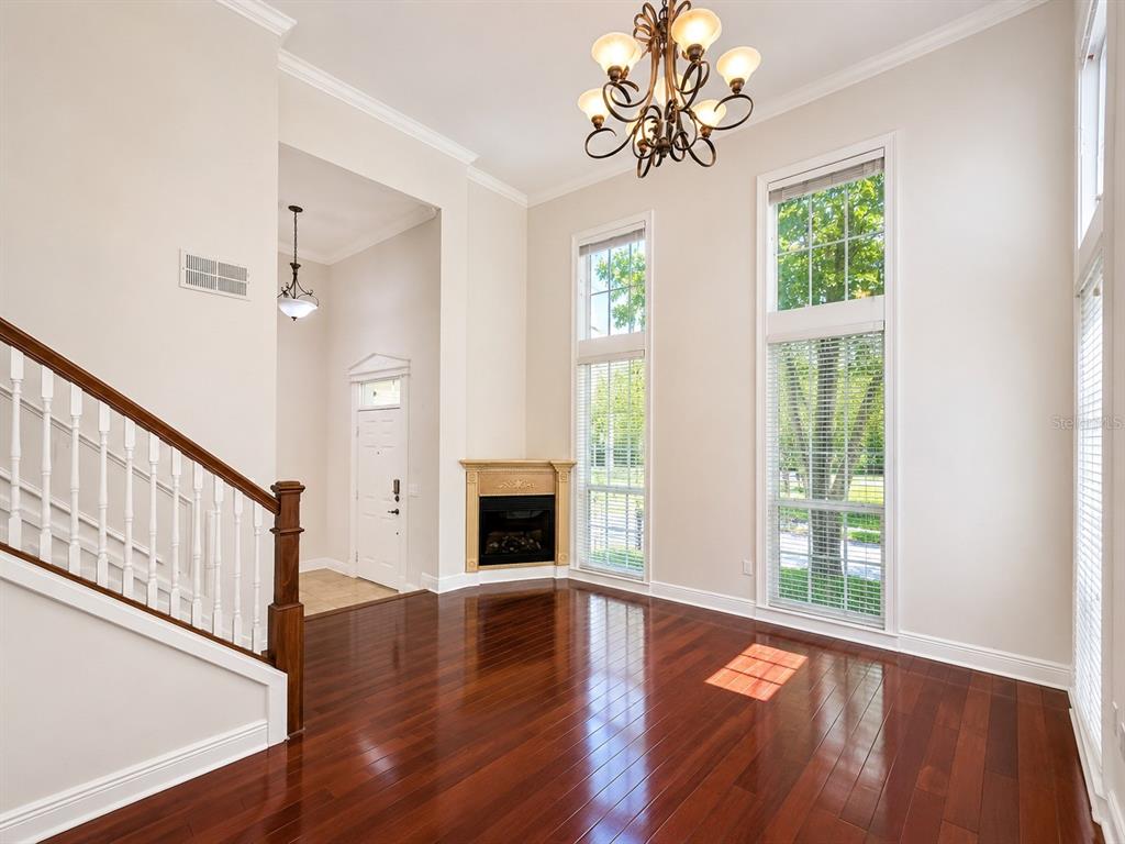 A living room with hardwood floors, a corner fireplace, tall windows, and a chandelier — 426 WATER STREET, CELEBRATION, FL