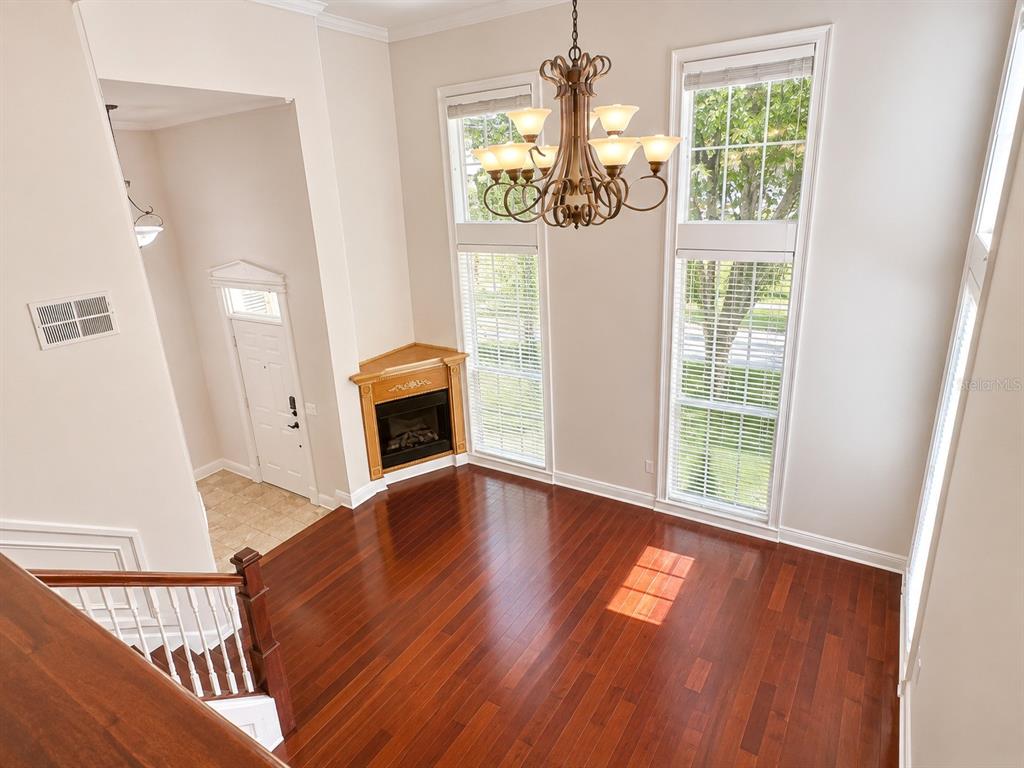 A high-ceilinged room features hardwood floors, a corner fireplace, and a large chandelier — 426 WATER STREET, CELEBRATION, FL