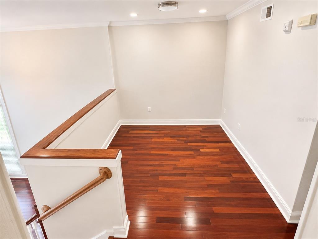 An interior view of a landing area featuring hardwood floors and a wooden staircase railing — 426 WATER STREET, CELEBRATION, FL