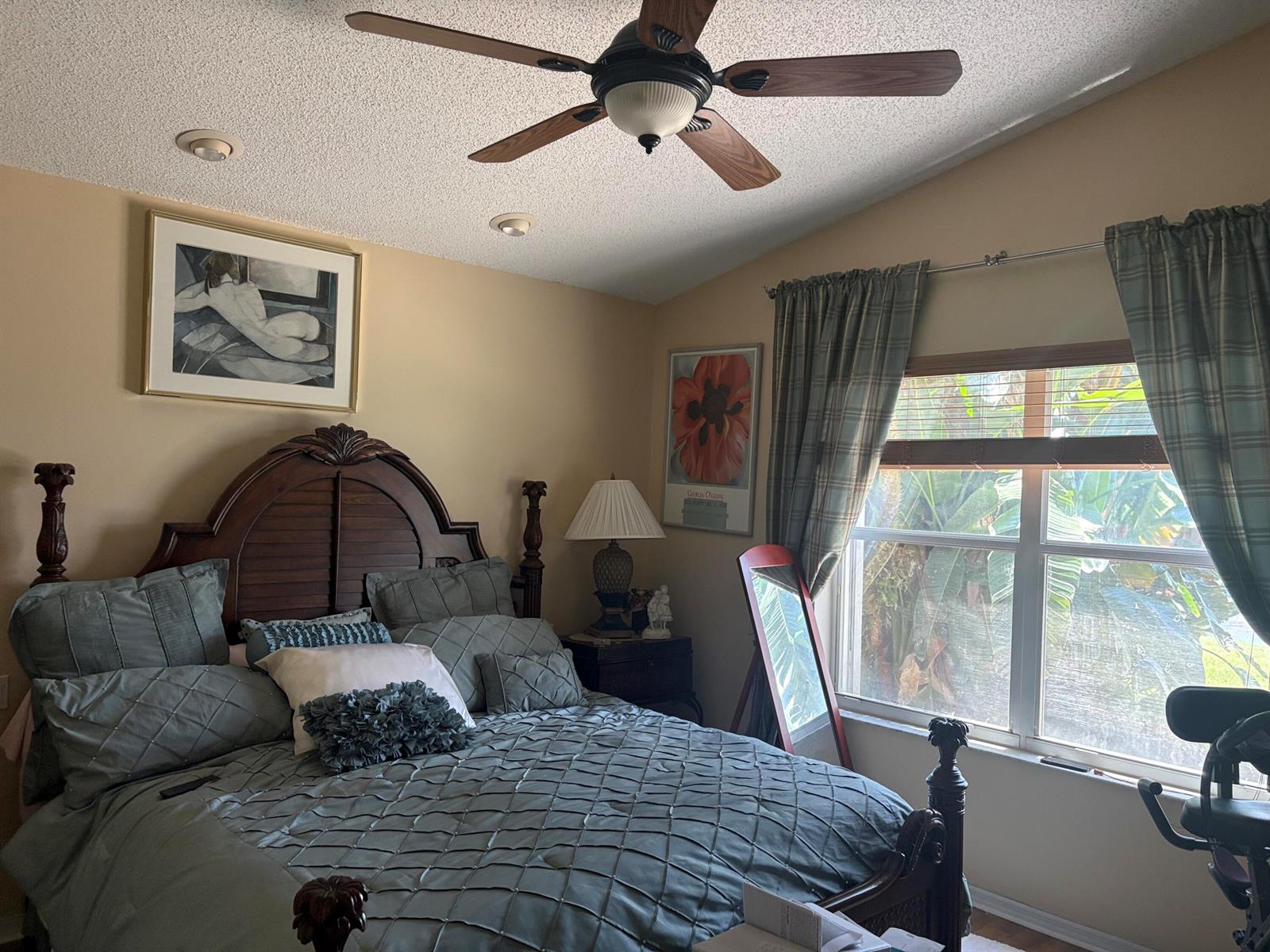 A bedroom features a wooden bed frame, blue bedding, a ceiling fan, and a window — 9815 Lemonwood Drive, Boynton Beach FL 33437, BOYNTON BEACH, FL