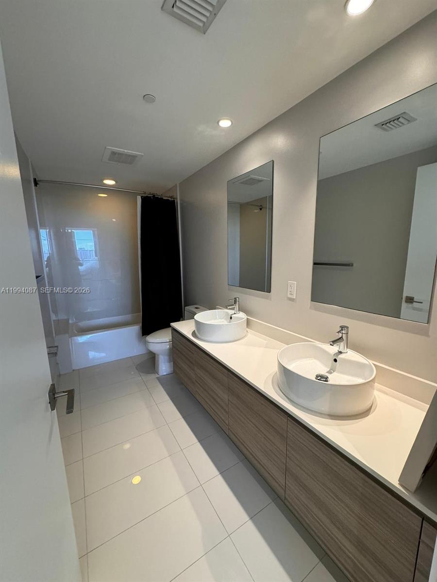 A modern bathroom features a double vanity with vessel sinks and a shower-tub combination — 121 NE 34th St # 807, Miami FL 33137, MIAMI, FL