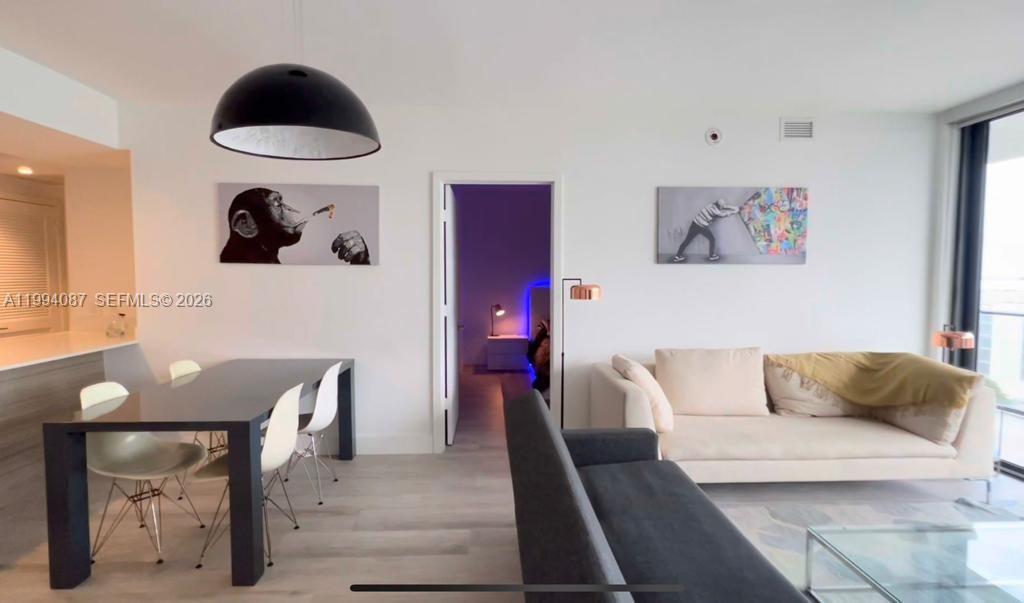 A modern living and dining area features white walls, light wood floors, and contemporary furniture — 121 NE 34th St # 807, Miami FL 33137, MIAMI, FL
