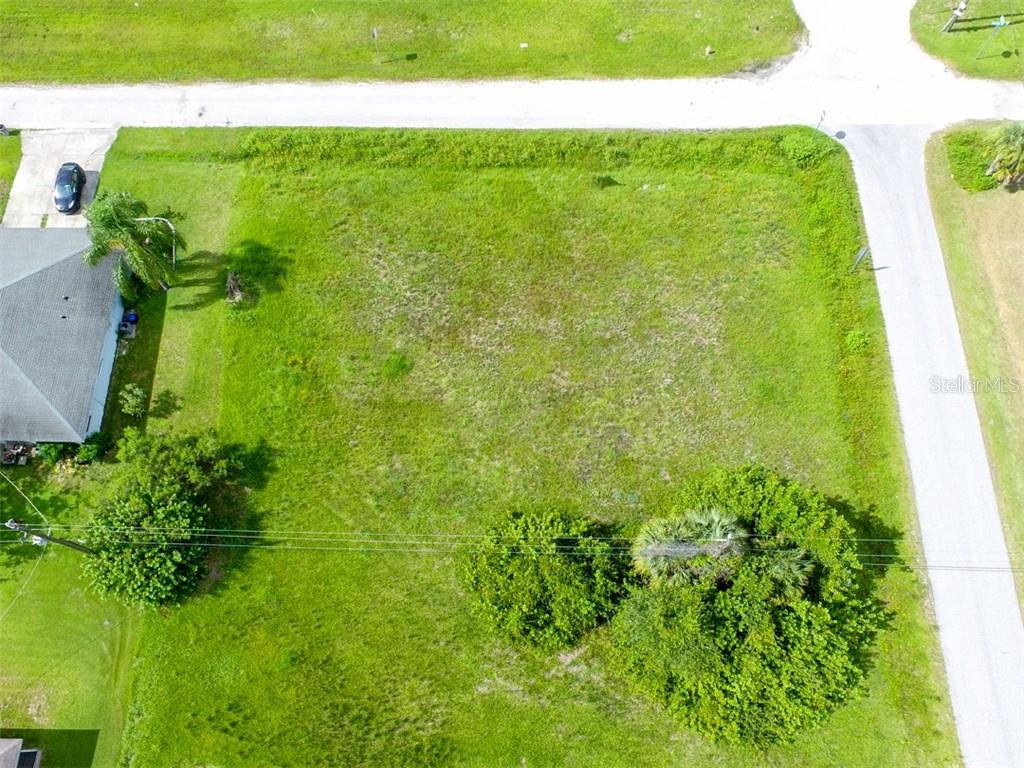 An aerial view shows a vacant, grass-covered rectangular lot situated between two paved roads — 12000 S TAMIAMI LOT 17 &18 TRAIL UNIT Front, NORTH PORT, FL