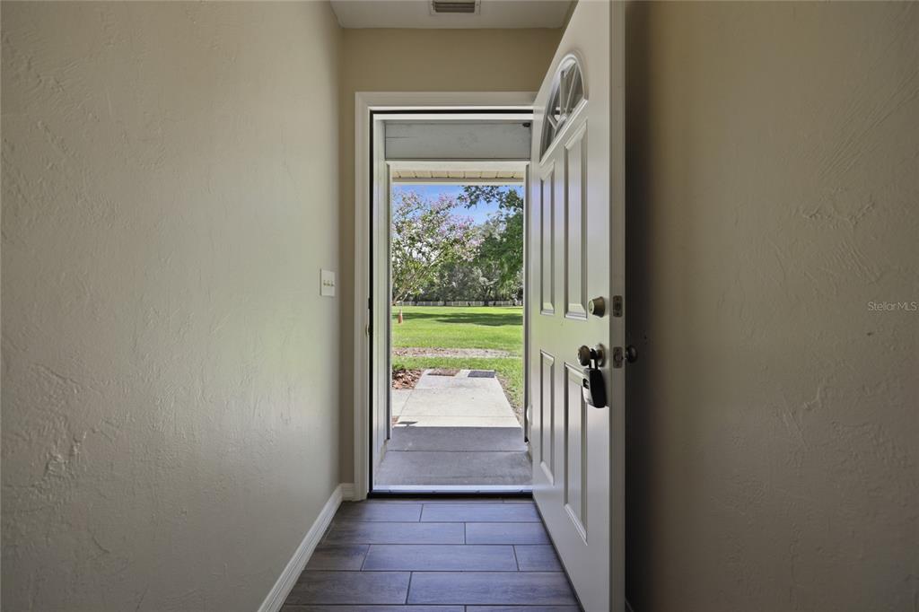 An open front door reveals a view of a grassy yard from a tiled entryway — 16310 NW 40TH PLACE, NEWBERRY, FL
