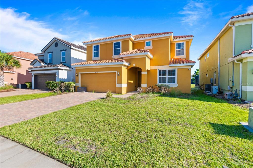A two-story yellow stucco house with a tiled roof and a two-car garage — 4445 SHIVA LOOP, KISSIMMEE, FL