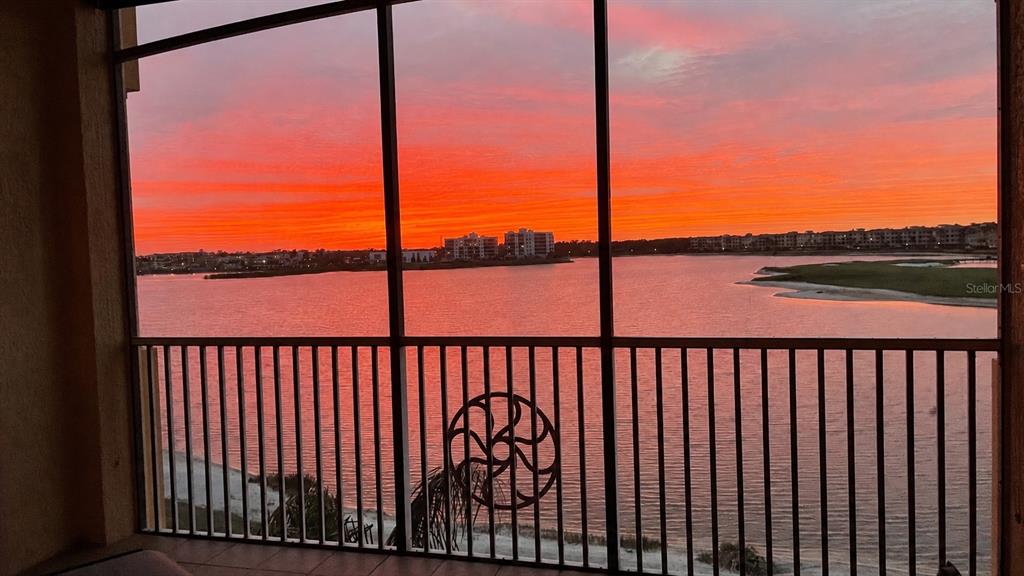 A screened-in balcony overlooks a lake and golf course under a blue sky — 6474 WATERCREST WAY UNIT 403, LAKEWOOD RANCH, FL