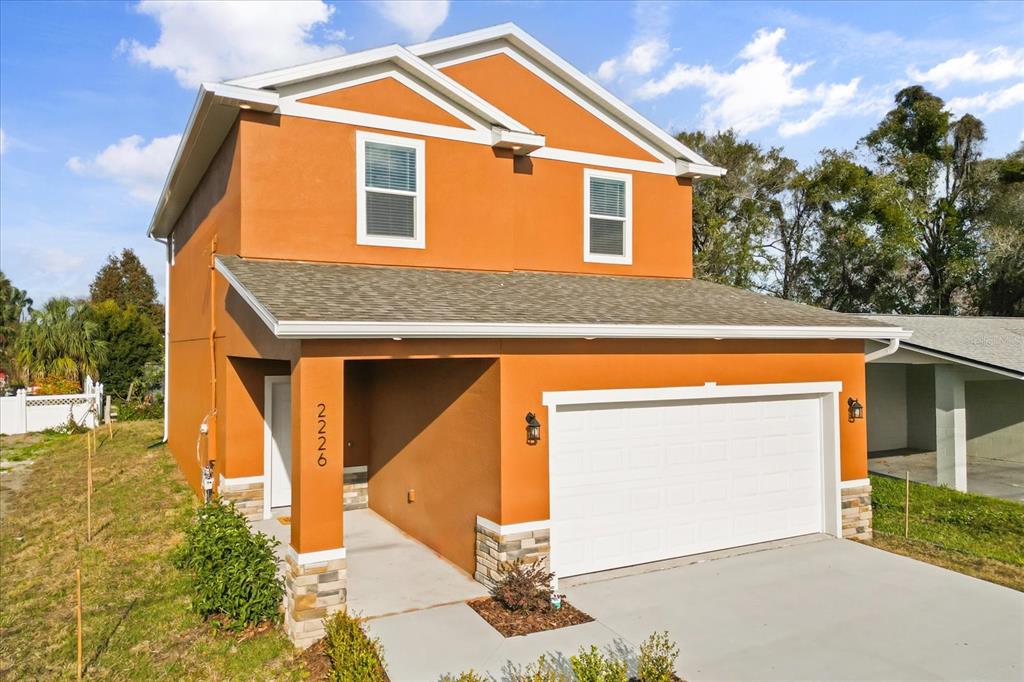A two-story house with orange stucco siding, a two-car garage, and stone accents — 2226 SOUTHWEST ROAD, SANFORD, FL