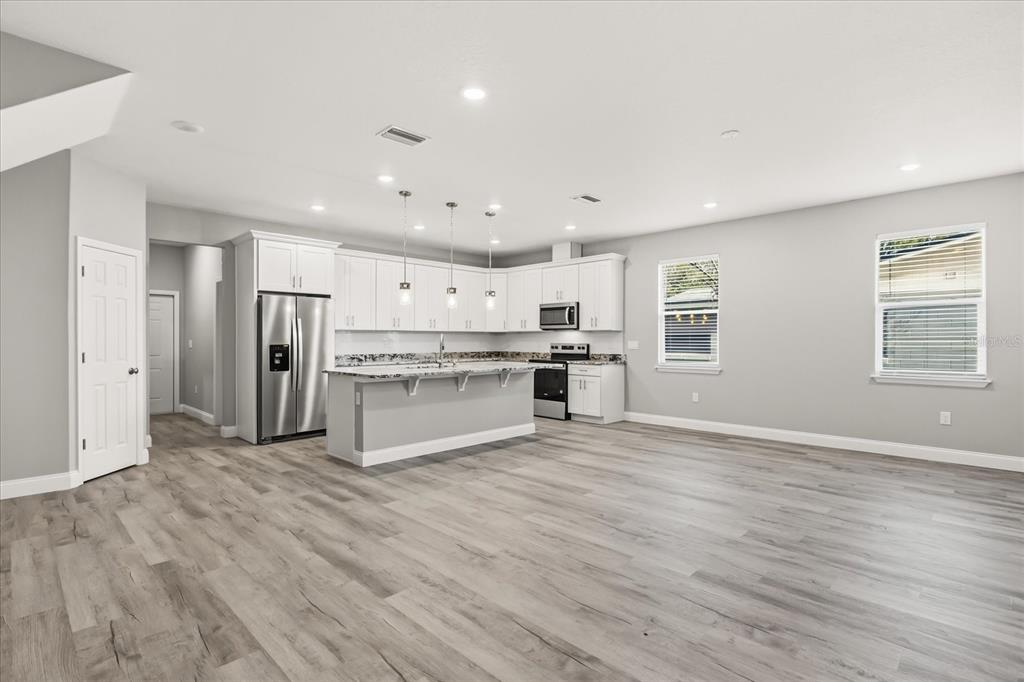A modern kitchen features white cabinetry, a center island, and light wood-look flooring — 2226 SOUTHWEST ROAD, SANFORD, FL