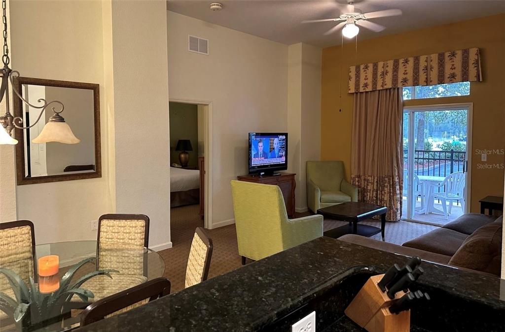 A living room and dining area with a kitchen counter, television, and sliding glass doors — 8100 POINCIANA BOULEVARD UNIT 2203, ORLANDO, FL