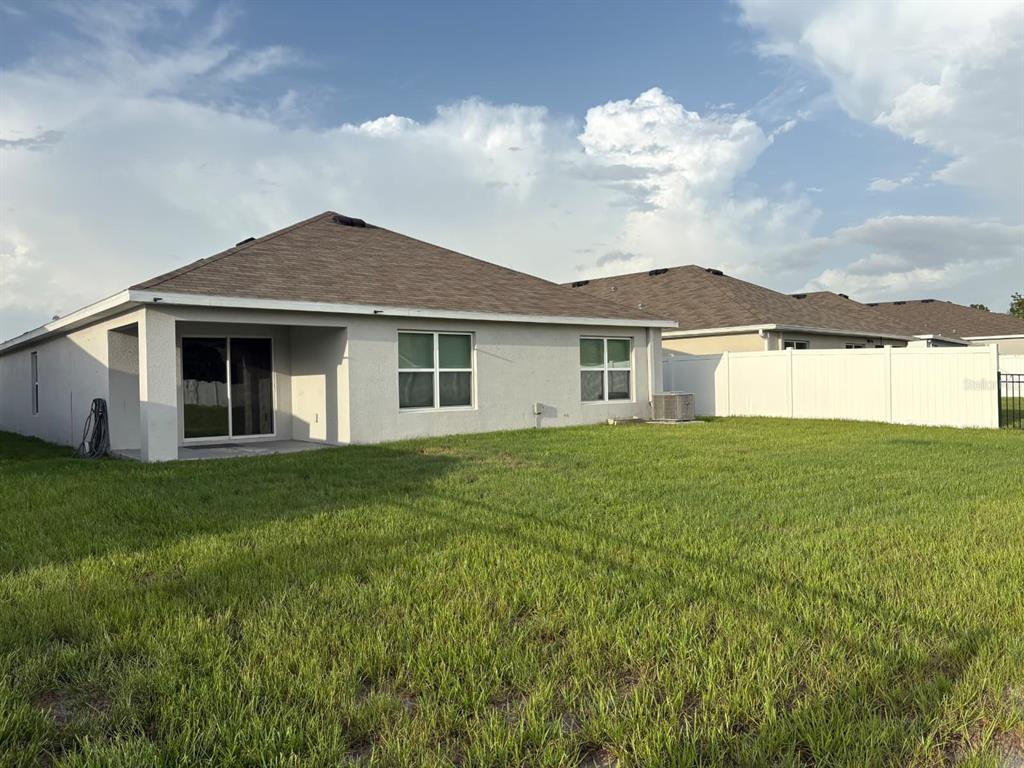 The rear exterior of a single-story house features a covered patio and a fenced yard — 3933 AUTUMN AMBER DRIVE, SPRING HILL, FL