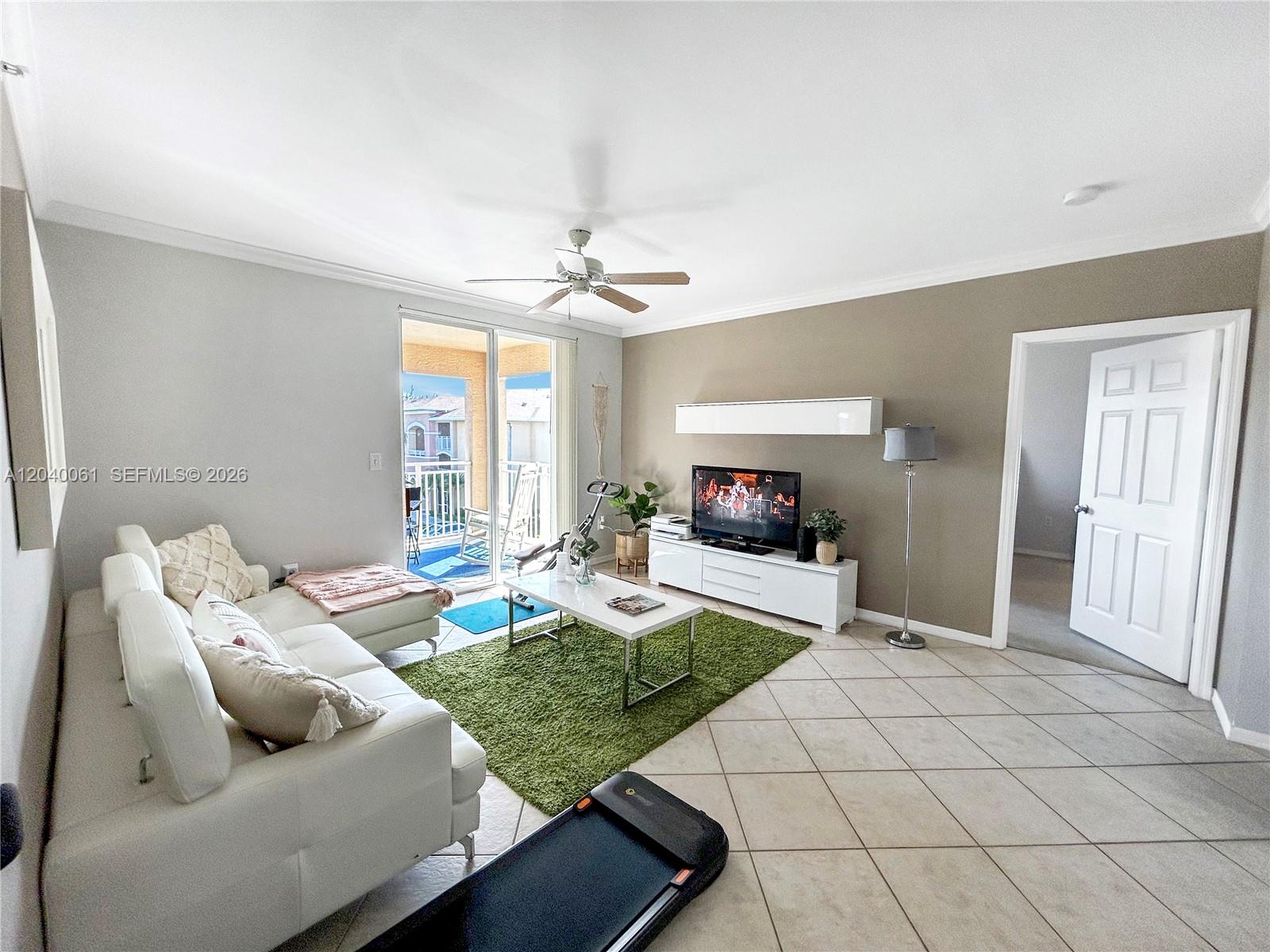 A living room features white tile floors, a green area rug, and a sliding glass door — 6458 Emerald Dunes Dr # 303, West Palm Beach FL 33411, WEST PALM BEACH, FL