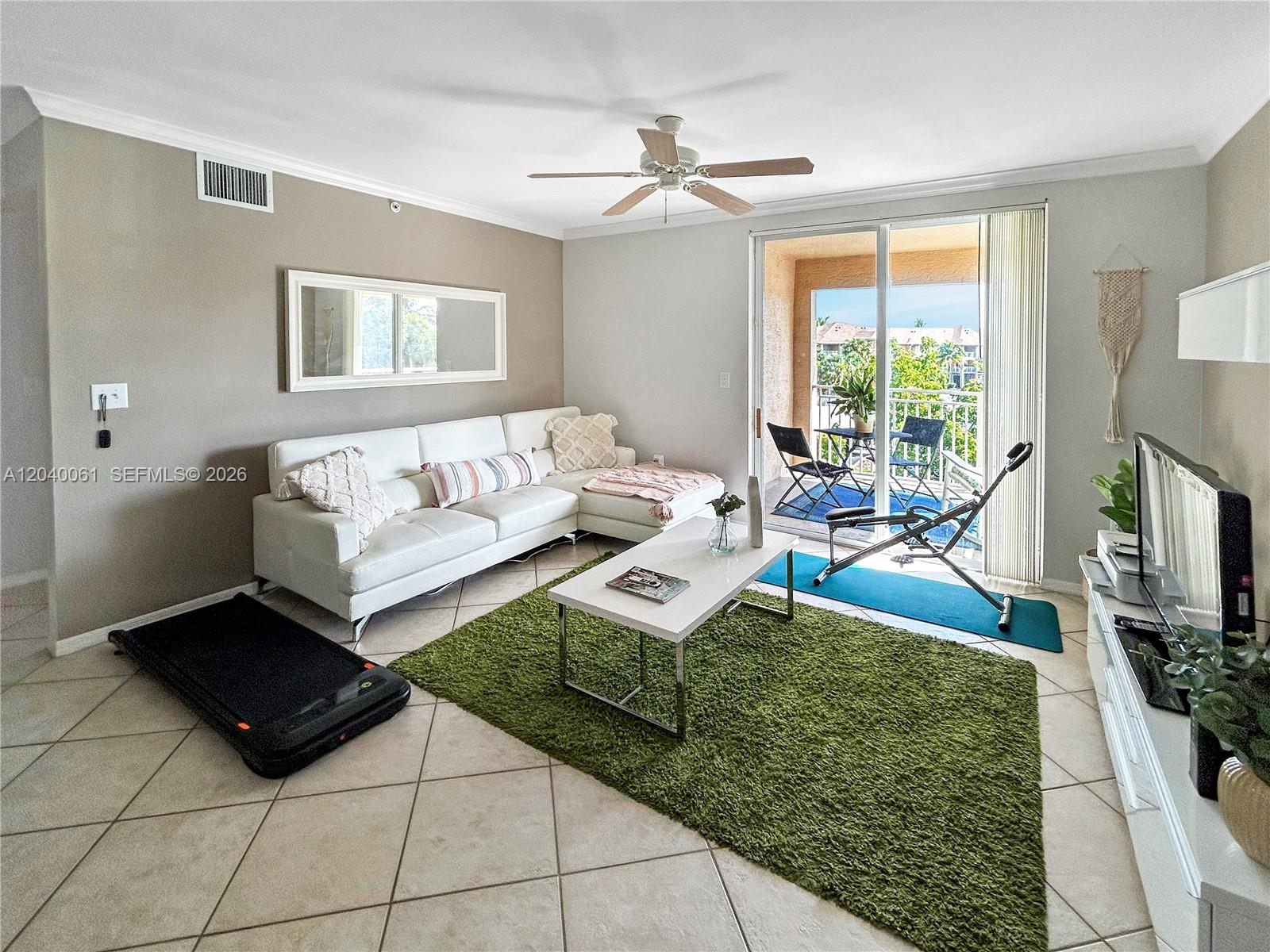 A living room features a white sectional sofa, green area rug, and a balcony view — 6458 Emerald Dunes Dr # 303, West Palm Beach FL 33411, WEST PALM BEACH, FL