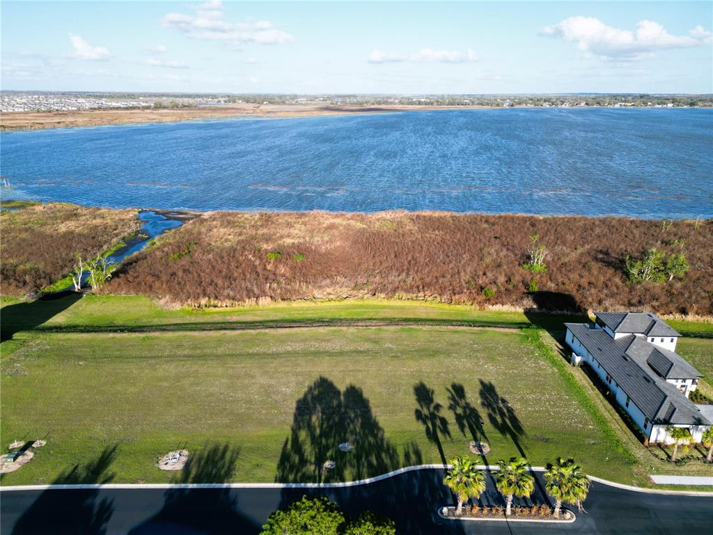 An aerial view shows a vacant residential lot next to a house and a lake — 344 CALADIUM AVENUE, LAKE ALFRED, FL