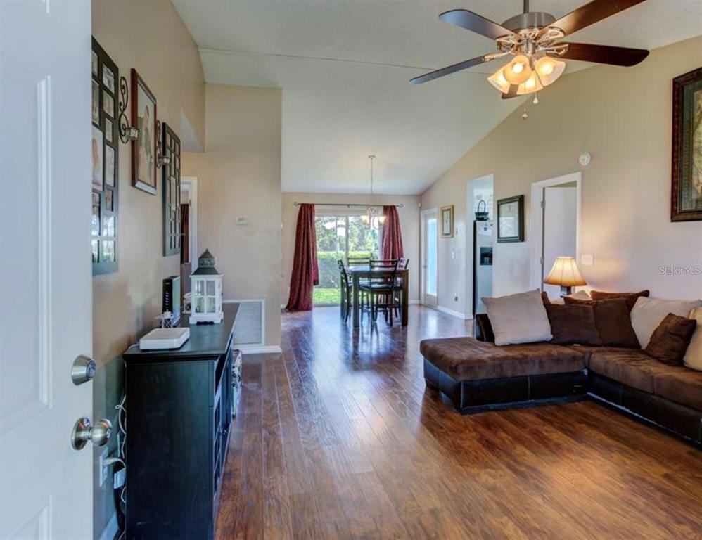 A living room with hardwood floors leads to a dining area with sliding glass doors — 1730 TROPICAL COURT, TAVARES, FL