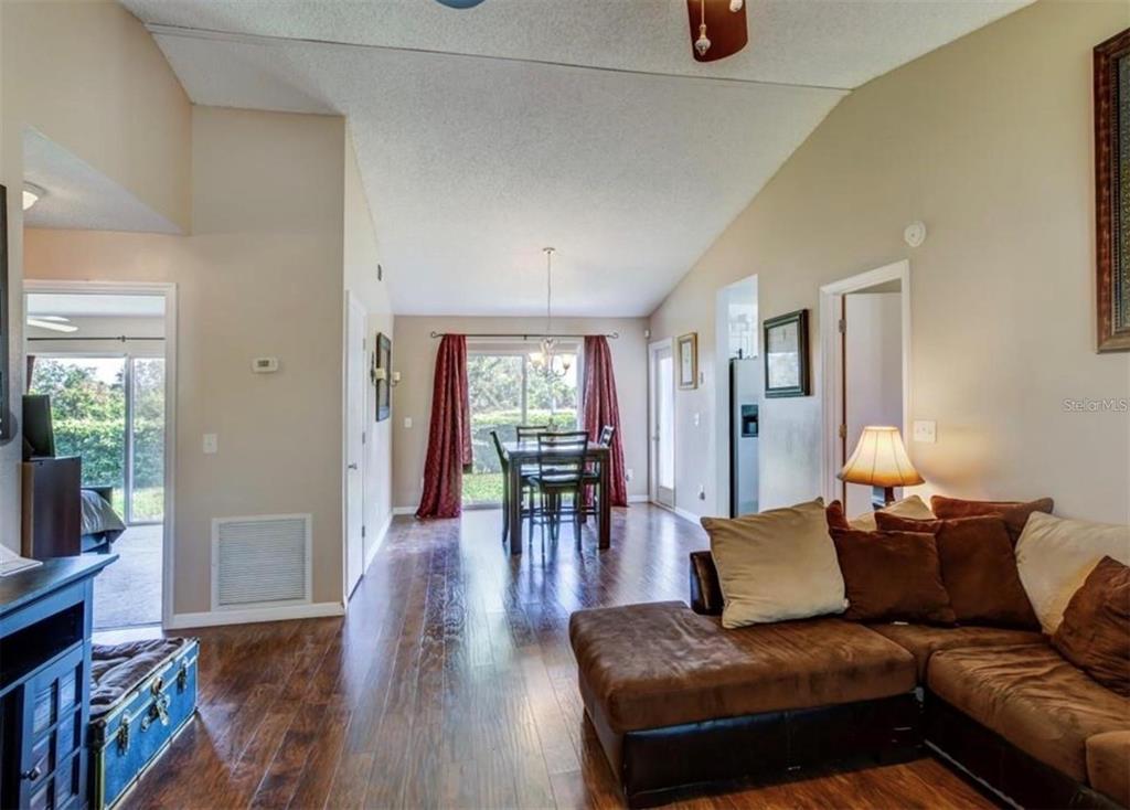 A living room with wood floors leads to a dining area with sliding glass doors — 1730 TROPICAL COURT, TAVARES, FL