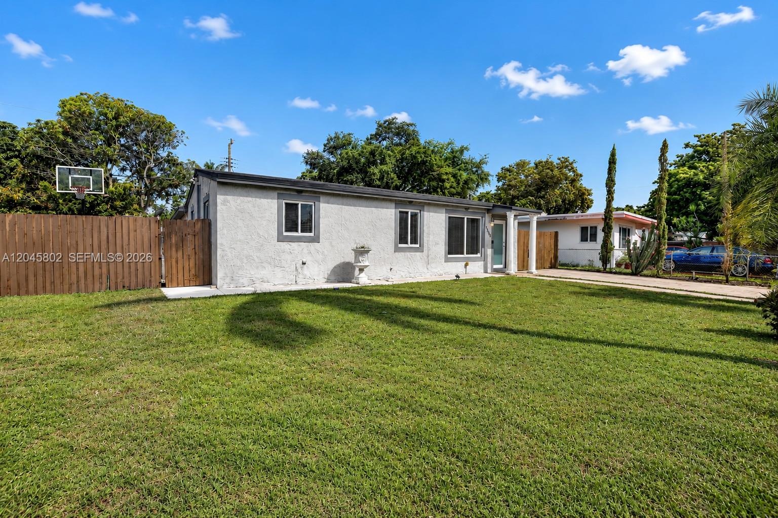 A backyard features a swimming pool with a rock waterfall, slide, and lounge chairs — 1300 N 70th Ter, Hollywood FL 33024, HOLLYWOOD, FL